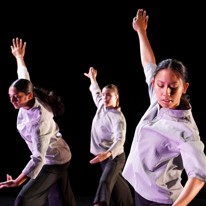 Dancers in white shirts performing during a concert.